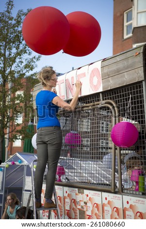 Amsterdam, The Netherlands, 12 September 2014, at West\'ival, a free open air Cinema and culture festival on Mercatorplein. preparation before the screening, preparation, woman hanging balloon
