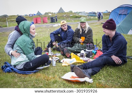 Traena, Norway - July 10 2015: group of friends having a drink and snack at the campsite, Traenafestival, music festival taking place on the small island of Traena