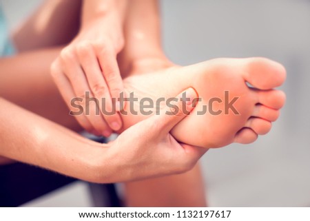 Pain in the foot, girl holds her hands to her feet, foot massage, cramp, muscular spasm, red accent on the foot, close-up Stock fotó © 