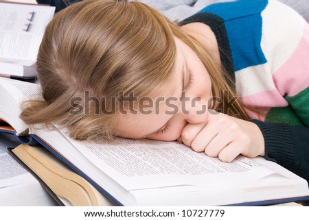 The young tired student sleeps on books