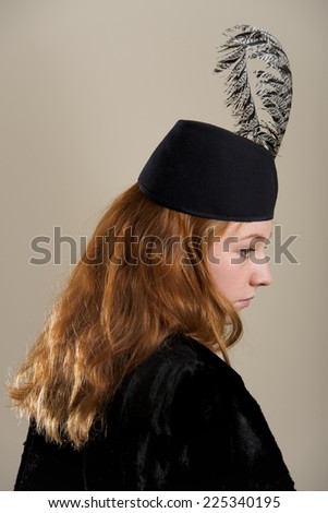 Redhead in black feathered hat in profile