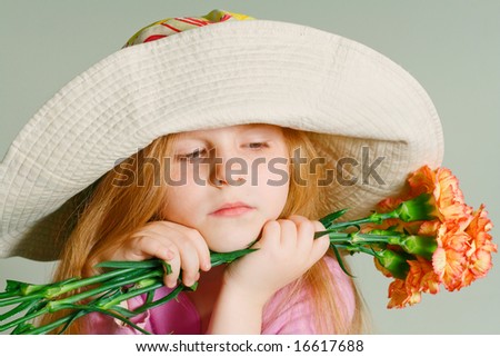 Small pensive girl in a big hat with pink flowers