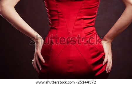 Woman back in red silk dress on dark background