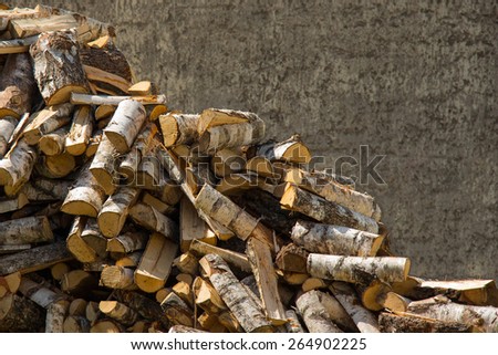 A pile of chopped birch firewood prepared to be stacked outdoors.