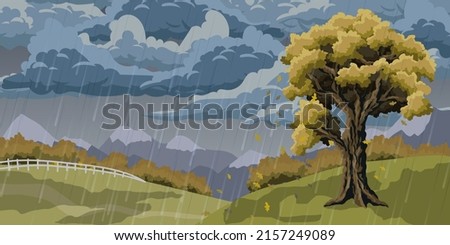 autumn landscape with a tree on a hill. Cloudy and rainy autumn day. Leaves fall from oak. Yellowed forest and mountains in the background.