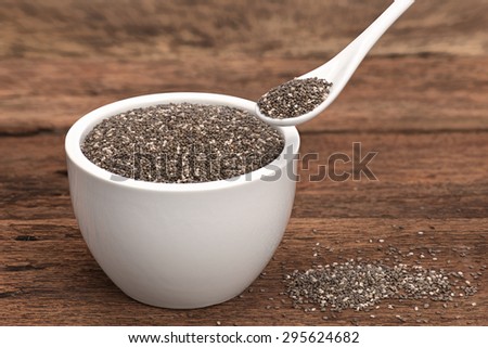 Dry chia seeds healthy super food in a white cup and in a white spoon place on old rustic look timber background