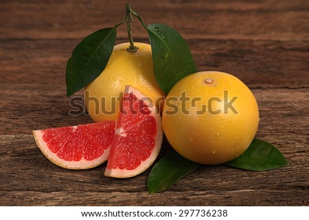 Fresh ripe ruby grapefruit and slices with leaves on old rustic look timber