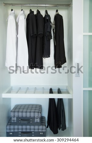 Clothes hang on a shelf in a designer clothes store, modern closet with row of cloths hanging in wardrobe, vintage rooms.