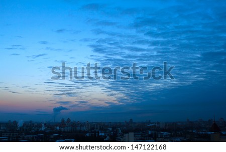 Calm and dramatic morning cloudscape in city, overcast sky, blue tones