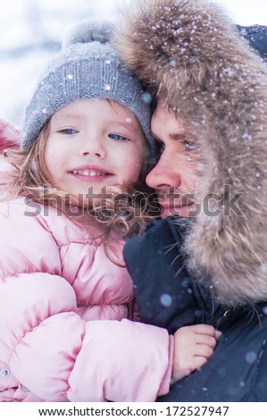 Father and daughter enjoying first snow blowing
