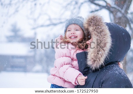 Father and daughter enjoying first snow blowing
