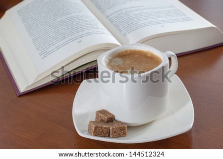 enjoying a good book and a cup of coffee with brown sugar on wooden table