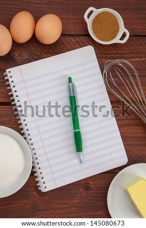 Just above the sight of a table full of ingredients and a notebook to prepare a cake recipe