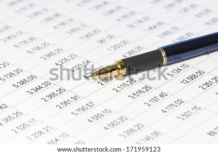 Close up of ballpoint pen over financial figures (very shallow dof, focus on pen tip)