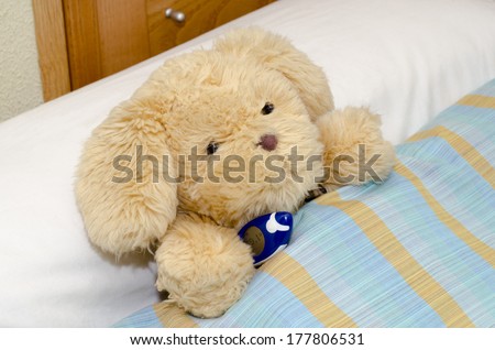 sick teddy bear in bed with thermometer