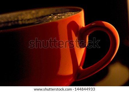 Detail of filled, red coffee cup, the shadow from the handle forms a heart with handle.