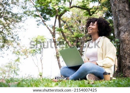 Beautiful Africa American woman relaxing after work hard and using laptop while leisure and shopping products in the park. Technology and freedom communication everywhere in all locations Photo stock © 