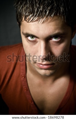 Low key portrait of intense looking guy with green eyes