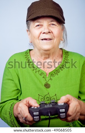 Happy senior woman playing video games with gamepad