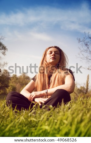Calm young woman relaxing in sunny grass field