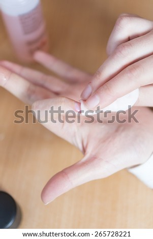 Woman removing nail varnish with acetone on a small cotton pad on the edge of a hand basin as she cares for her nails and cuticles in a health and beauty concept