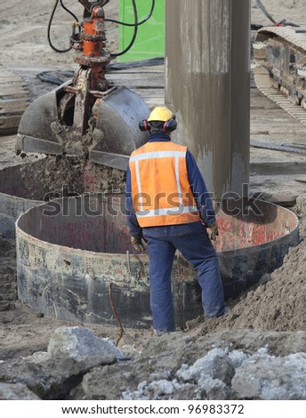 Worker wearing reflective vest and ear protection at a construction site