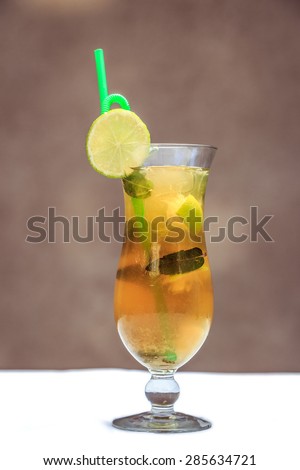 Golden iced tea with green straw and mint