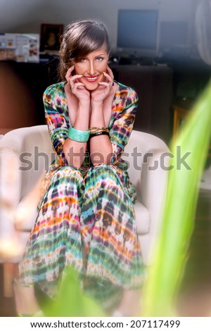 smiling Young woman sitting in a chair,in a colored dress,general plan