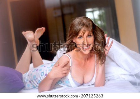 happy woman on the bed in the morning,smiling woman lying on a white bed.