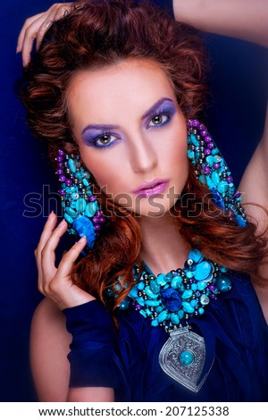 Portrait of red-haired girl in lilac tones, makeup and jewelry blue-lilac tone