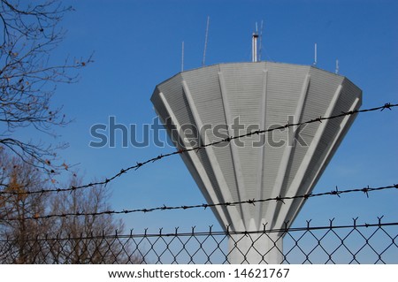 Fence and conical water tower behind it. Focus on the fence.