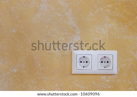 Electric wall plug at a orange wall