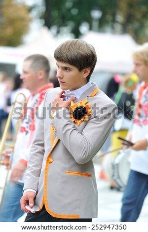 KIEV, UKRAINE - AUGUST 24: Young guy with sunflower on his jacket is correcting the bow tie and he is a little worried about his upcoming performance at Independence Day on August 24, 2013 in Kiev