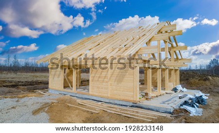 House under construction on sky background. Frame of a tree house. Concept - construction of frame houses. Erection of a cottage from wooden beams. Lumber for erection. Construction a country cottage Stockfoto © 