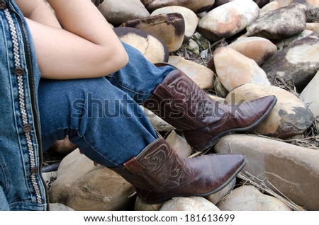 People wear jeans to wear boots, was sitting on a rock.