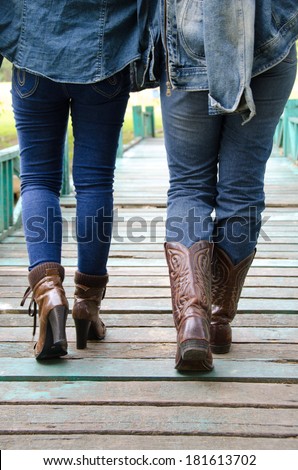 People wear jeans to wear boots walking on a wooden bridge.