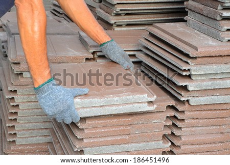 A worker moving brown roof shingles.