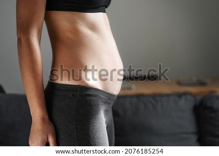 Young woman side view of body. Swollen belly. Pregnancy. Diastasis recti after child birth. Fitness exercises and diet for weight loss.  Stockfoto © 