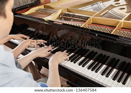 Two people, a couple playing piano duet, showing mostly their hands