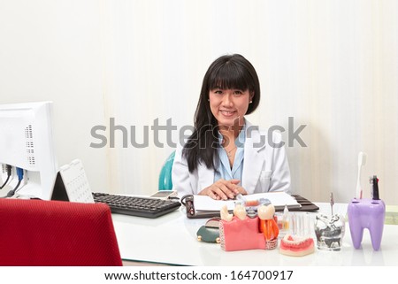 Young female dentist pose form her working desk in dental clinic