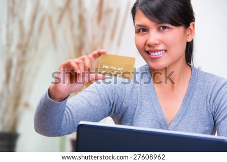 A young Asian woman showing her gold credit card.