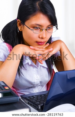 Front view of female scholar is looking at her laptop in the class