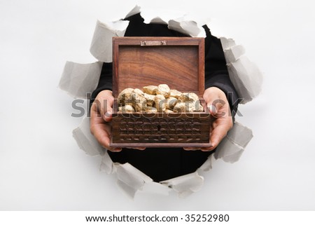 Hand breakthrough wall holding golden nuggets in treasure chest means breakthrough in finance or similar things - one of the breakthrough series