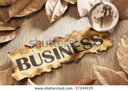 Global business concept using printed word on burnt paper along with compass and golden key, surrounded by dry leaf