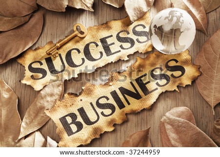 Key to success in global business concept using words printed on burnt paper and related objects, surrounded with dry leaf