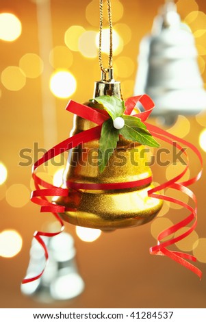 Golden Christmas Bell over warm background with blurred light