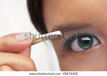 A young female using eyebrow tweezers PS:shallow depth of field