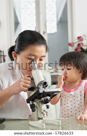 Little Chinese girl trying to distract her mom concentration from working on microscope