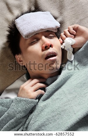 A sick male sleeping with wet towel on his forehead to reduce high high fever