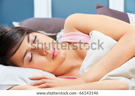 Young Asian female sleeping under blanket in her bedroom